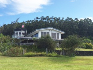 A simple cottage smaller than I was expecting, painted in a classic white with stone walls around the base, long glass windows across the front, and an unassuming but prominent tower poking out from the back.